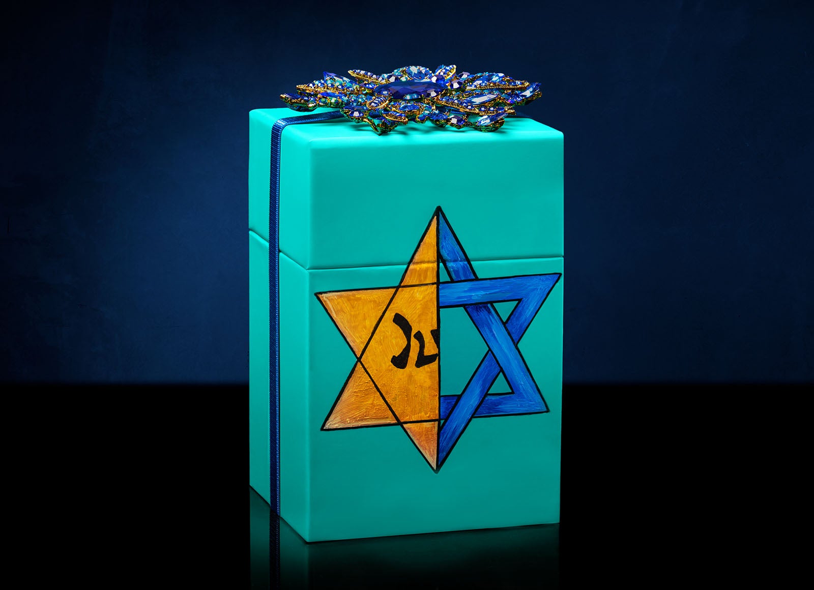 Our signature Tiek Blue box is hand painted with a powerful design juxtaposing a blue Star of David with the yellow patch Jews were forced to wear during the Holocaust.