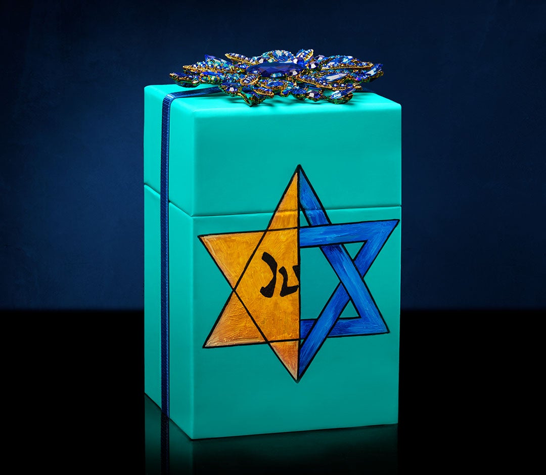 Our signature Tiek Blue box is hand painted with a powerful design juxtaposing a blue Star of David with the yellow patch Jews were forced to wear during the Holocaust.