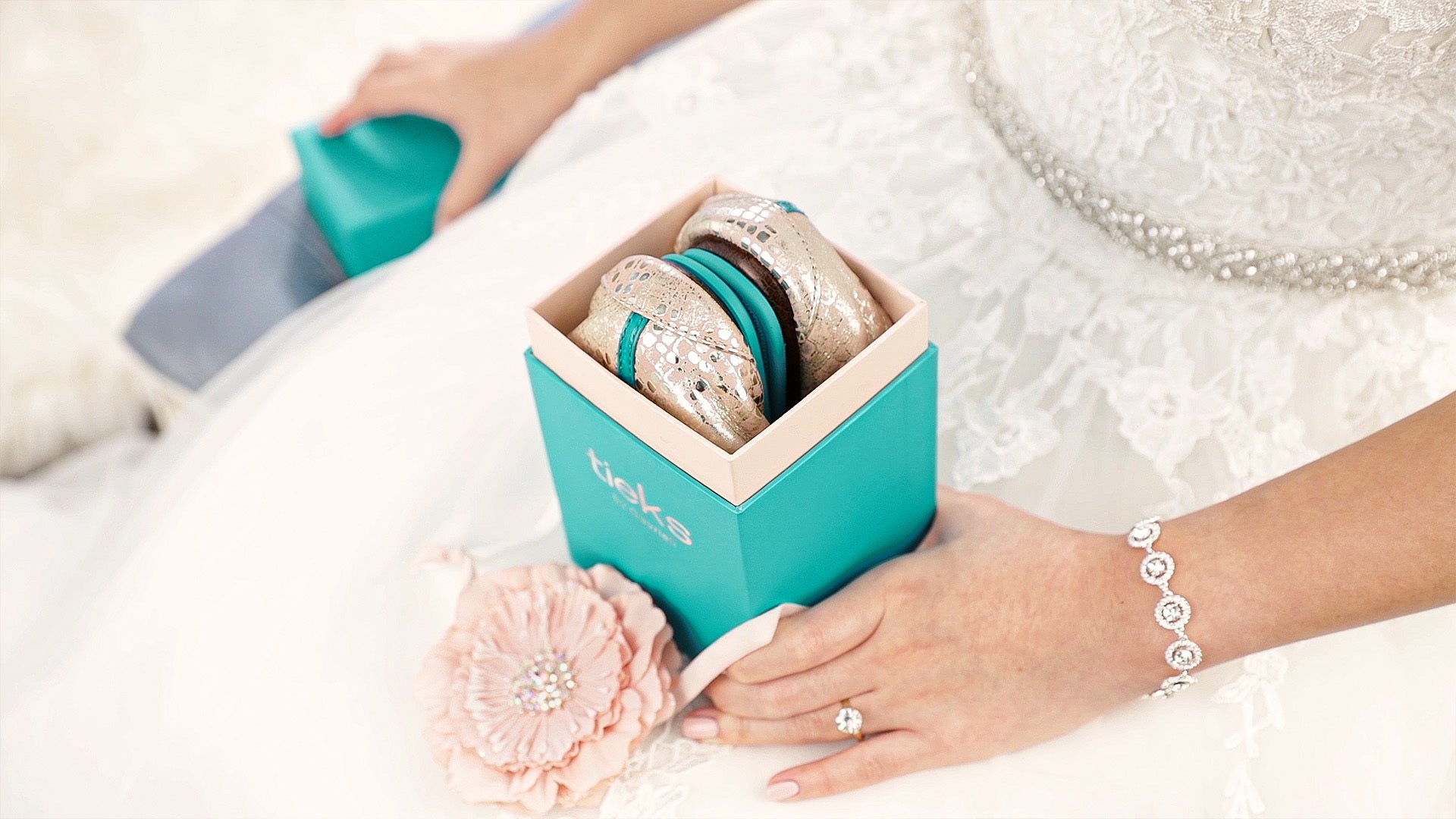 bride opening her wedding day tieks flats in her wedding dress