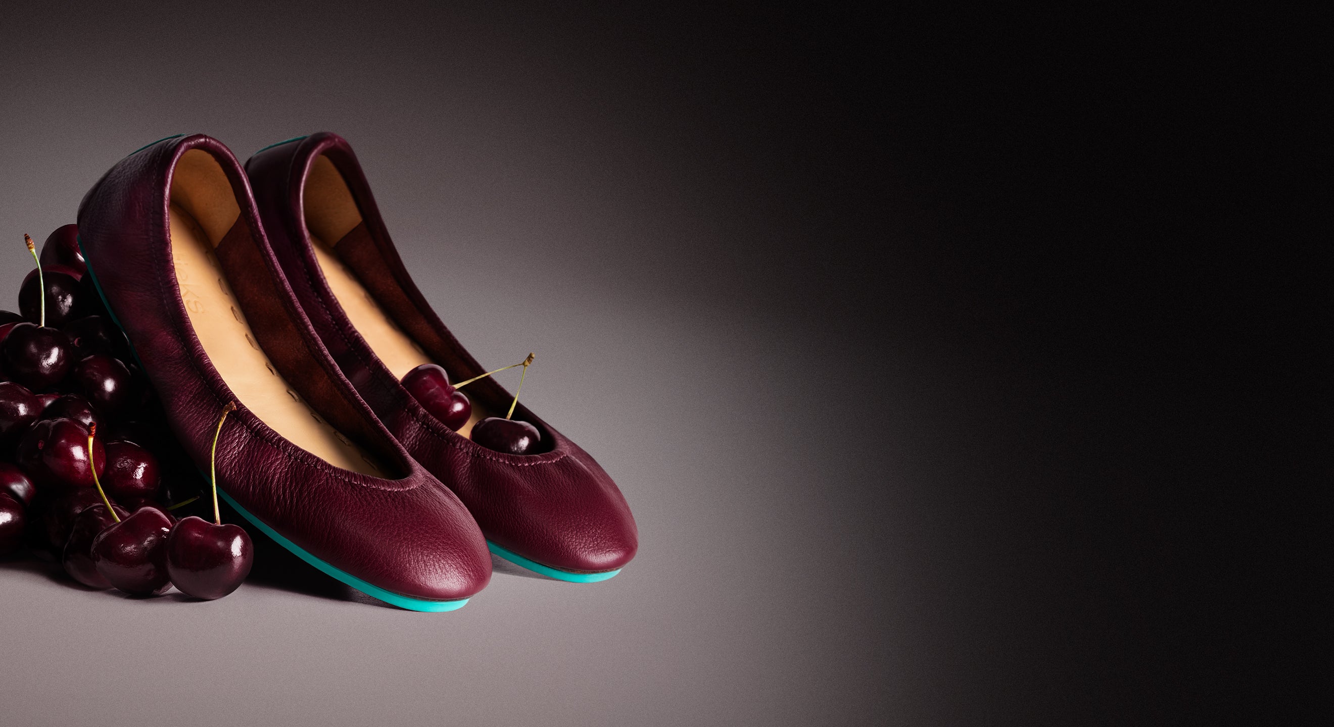 burgundy ballet flats sitting on a pile of cherries. 