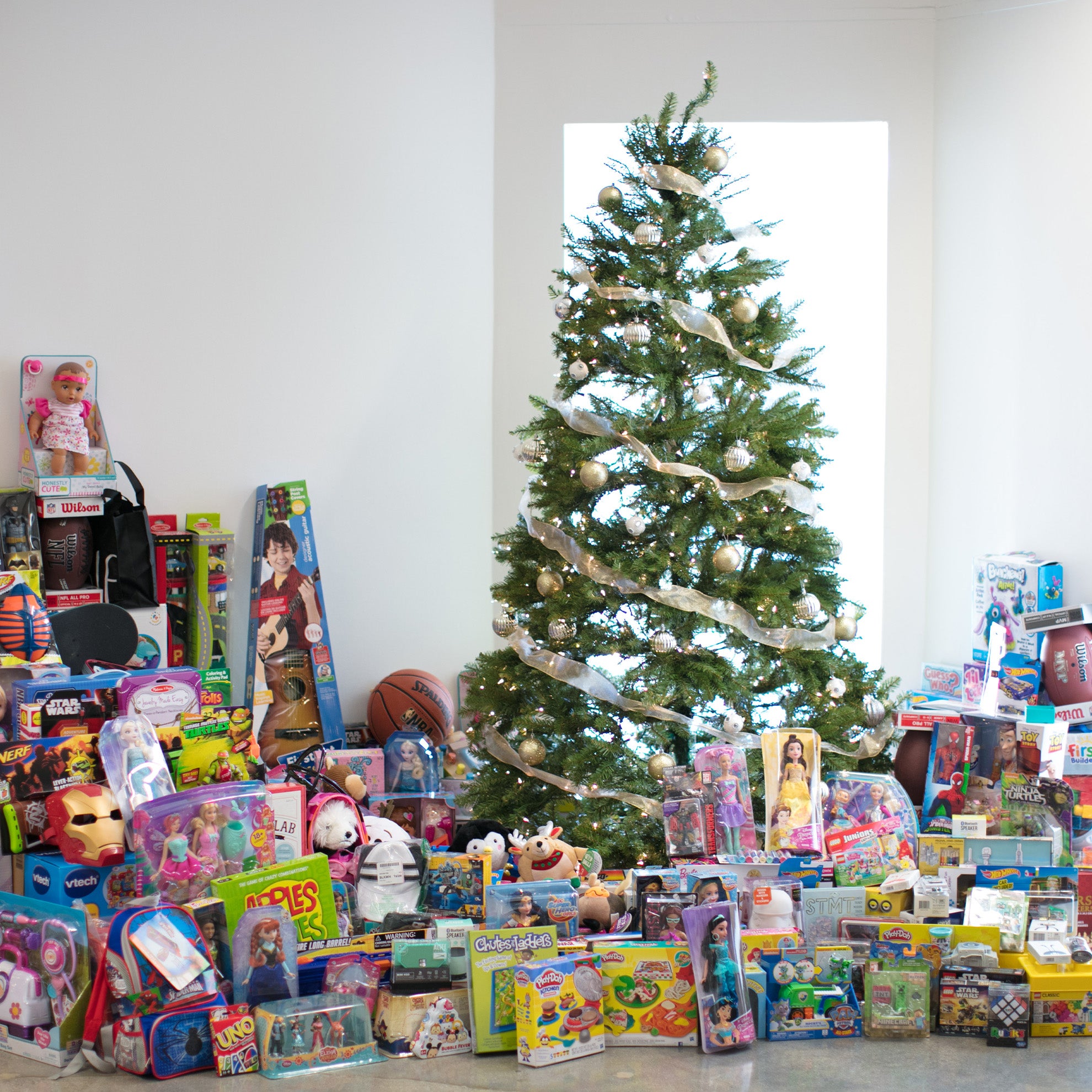 toys from the tieks toy drive piled high under the christmas tree