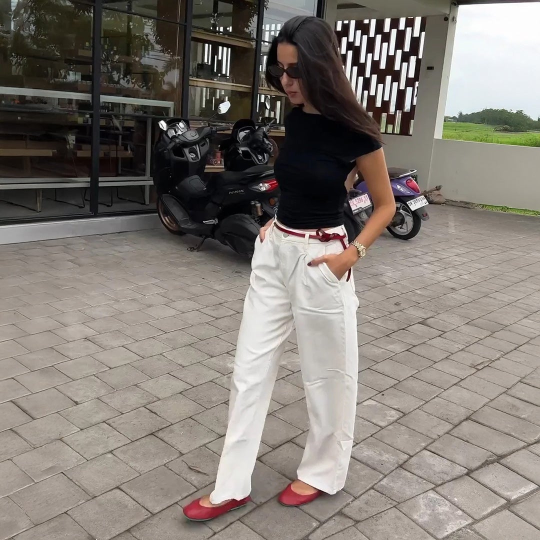 woman wearing cardinal red tieks flats with white jeans and a black top