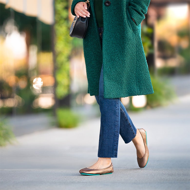 metallic bronze tieks flats styled with a green coat and jeans