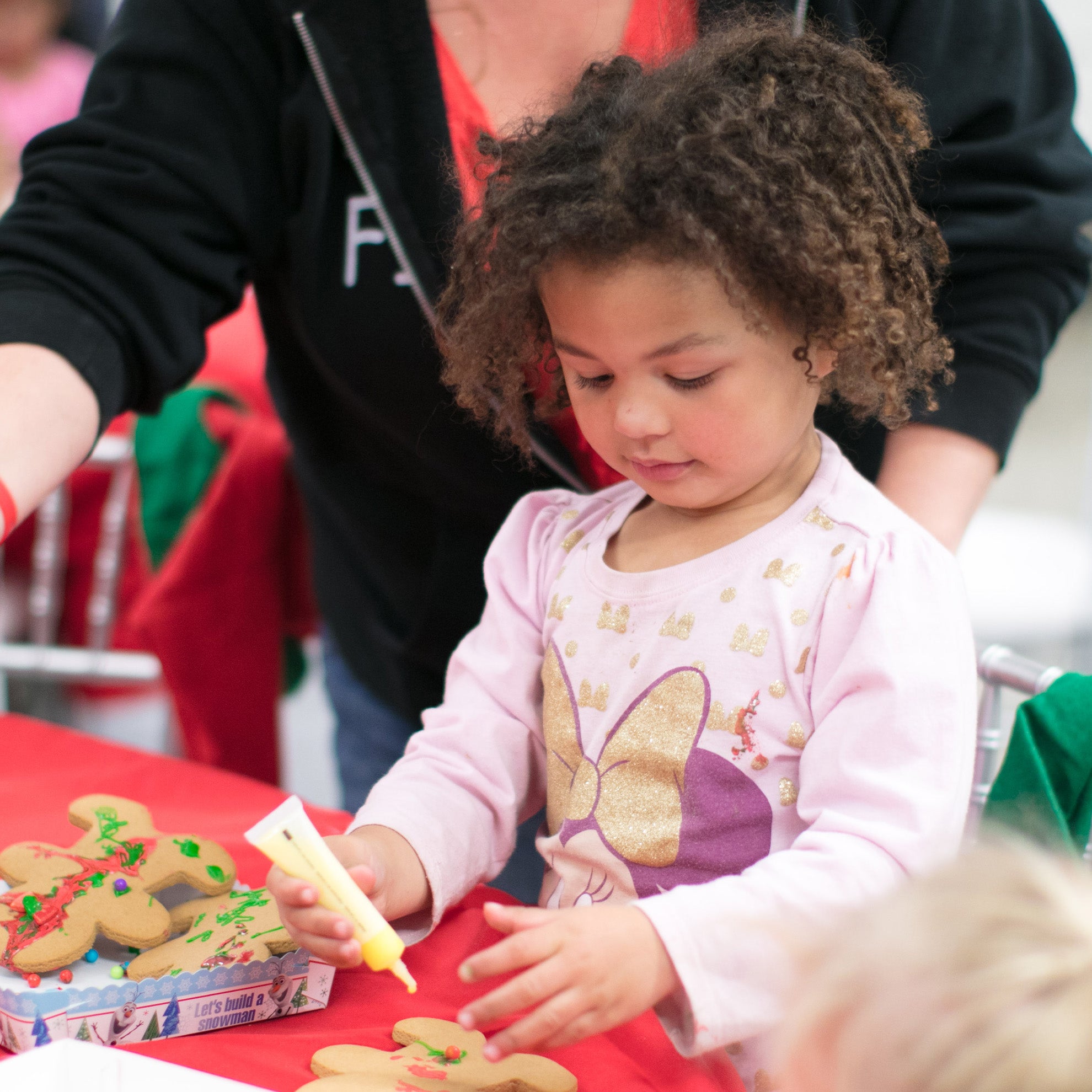 little girl decorating a gingerbread house