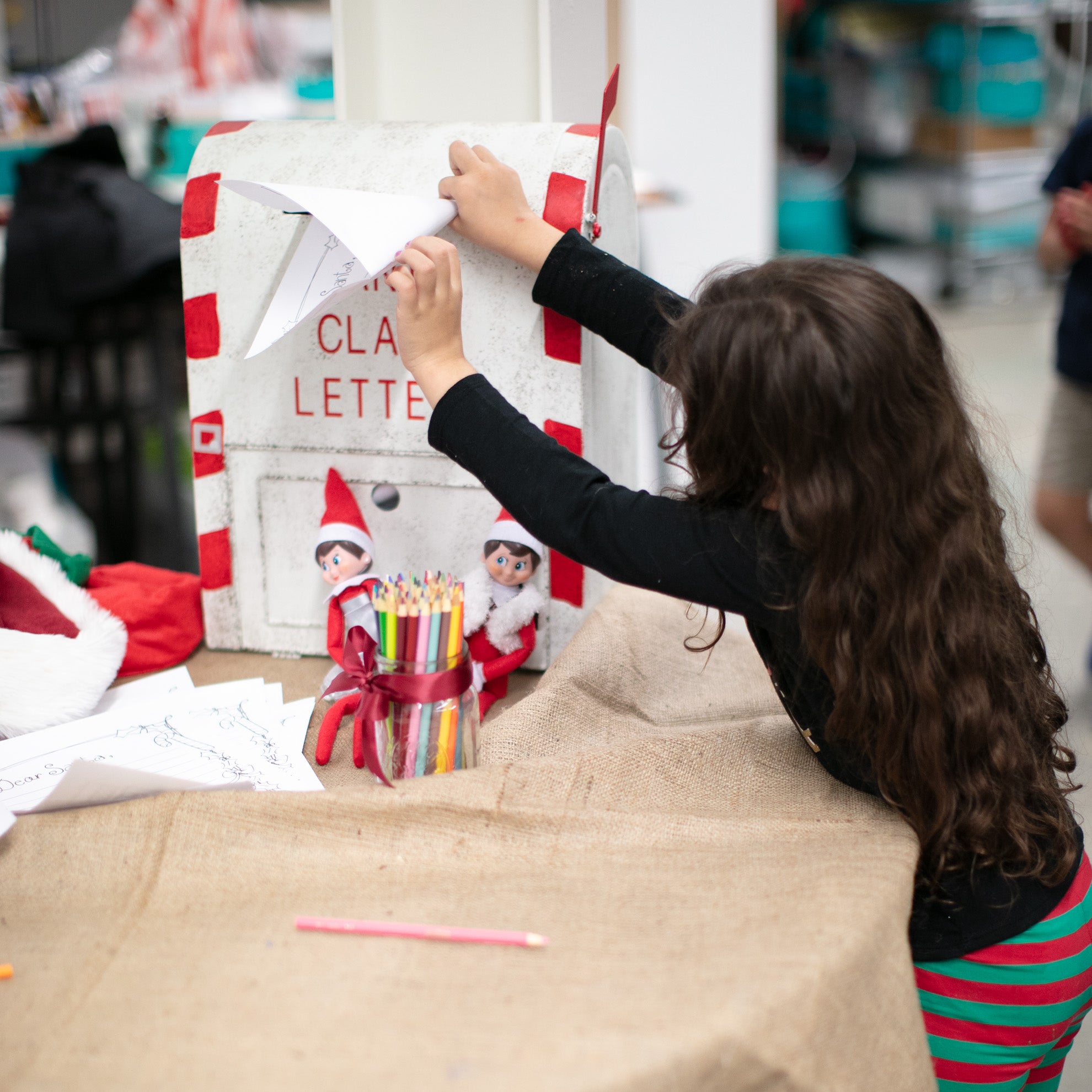 a little girl dropping her letter to santa in the mailbox