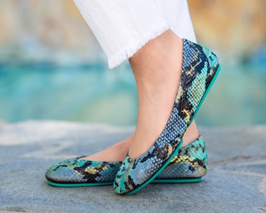 model wearing white pants and azure snake tieks flats