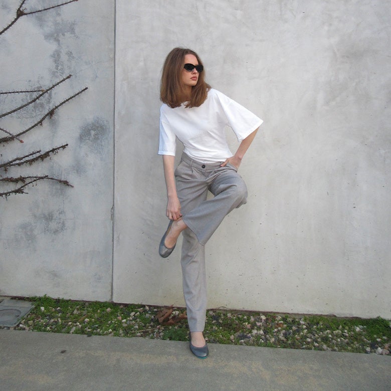 woman wearing white shirt, grey trousers, and pewter ballet flats