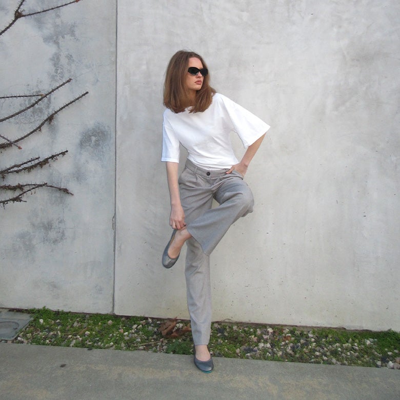 woman wearing pewter tieks flats with grey trousers and a white shirt