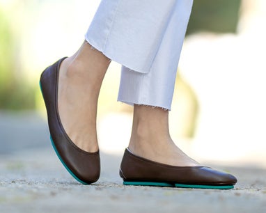 model wearing white jeans and chocolate brown tieks flats