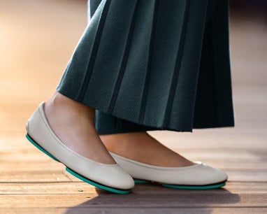 cream tieks flats paired with blue pleated pants