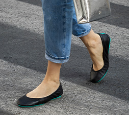 Close up of a woman wearing Matte Black Tieks leather ballet flat shoes.