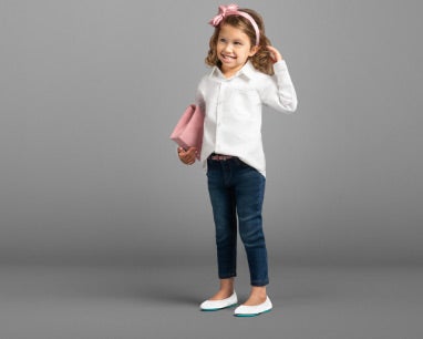 young girl wearing a white button-up top, jeans, and diamond white kids flats