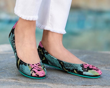 model wearing white pants and electric snake tieks flats