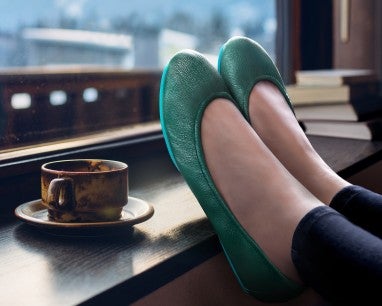 woman wearing pacific green tieks flats in a coffee shop