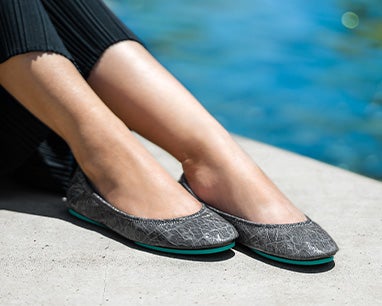 model wearing black pants and slate grey croc tieks flats by the water